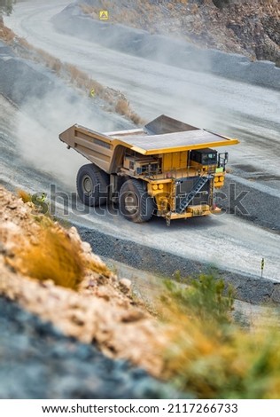open cast mining huge truck driven in the pit trail of dust behind