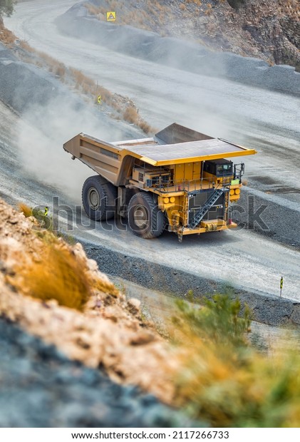 open cast mining huge truck driven in the pit\
trail of dust behind
