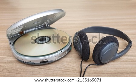 Open cd player with disk and earphone on wooden background.