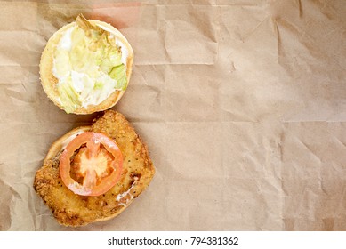open cheeseburger with chicken on the packaging paper