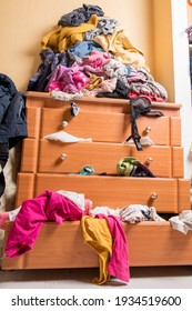 open chest drawers with drop-down clothes and piles of clothes around in a mess. Bottom view