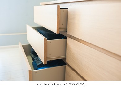 Open Chest Of Drawers Made Of Wood, Side View. Inside Are Things, Clothes, Jeans.