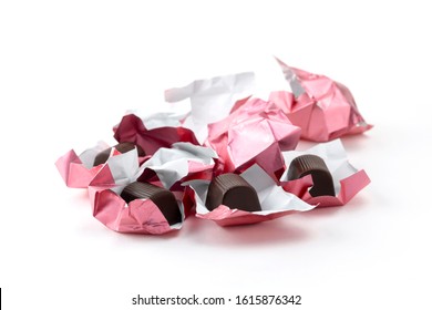 Open Chocolate Candies With Wrappers Isolated On A White Background.  Crumpled Pink The Wrapper From The Candy.