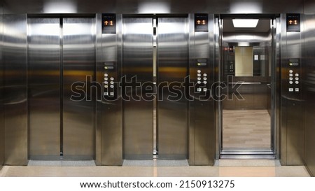 Open and closed chrome metal office building elevator doors realistic photo. Lift transportation floor to floors with push switch for up and down.