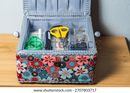Open colourful sewing box with scissors, needles and a measuring tape.  Needlecraft or hobby concept