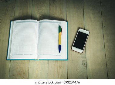 
Open Day Planner, Smartphone,  Ballpoint Pen On The Wooden Table