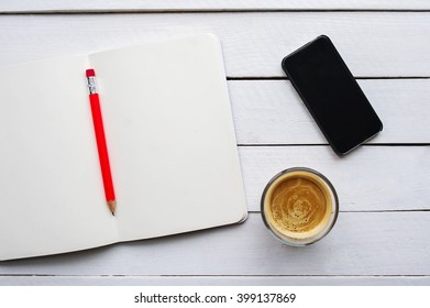 Open Day Planner, Smartphone, Ballpoint Pen, Cup Of Coffee On A Plate On The White Wooden Table.