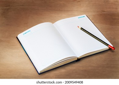 Open diary with a pencil lie on a wooden board, top view - Shutterstock ID 2009549408