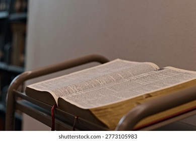 Open dictionary resting on a reading stand in a quiet indoor study setting, showing printed definitions and supporting language learning and reference use.