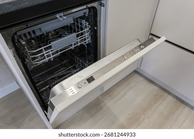 Open dishwasher with empty racks inside. The door has a control panel with buttons