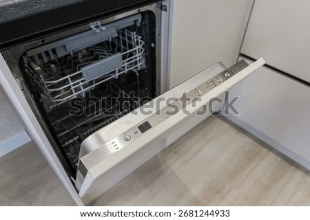 Open dishwasher with empty racks inside. The door has a control panel with buttons