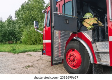 The open door of the fire truck cabin where the firefighters are located. The firefighter's protective clothing is in the cabin of the fire truck. The 911 rescue service. Equipment for saving people.