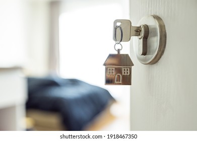 Öffnen Sie die Tür und den Türgriff mit einem Schlüssel und einem Schlüsselkettenförmigen Haus. Immobilieninvestition und Hypothekenfinanzgrundsatz