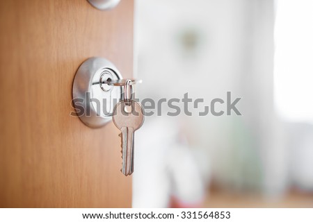 Open door with keys, key in keyhole, bedroom in background.