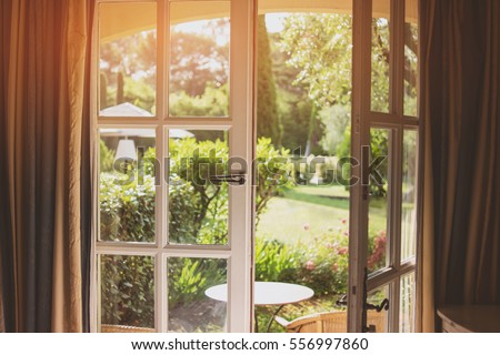 Open door and nature. Green plants and sunlight. House with a garden.
