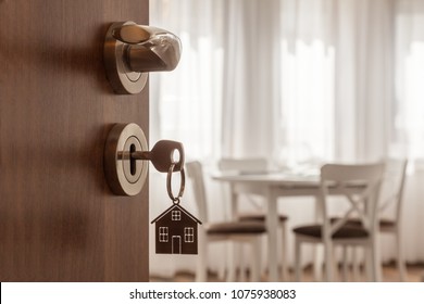 Open door to a new home. Door handle with key and home shaped keychain. Mortgage, investment, real estate, property and new home concept