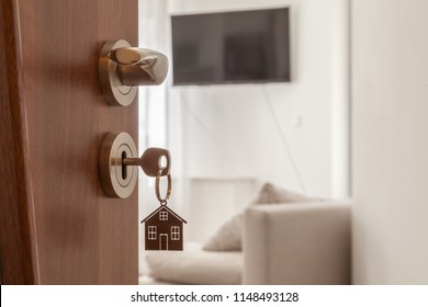 Open door to a new home. Door handle with key and home shaped keychain.  
