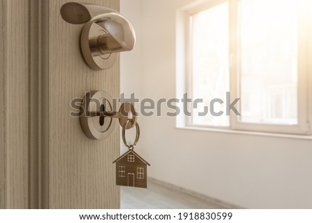 Open door to a new home with key and home shaped keychain. Mortgage, investment, real estate, property and new home concept
