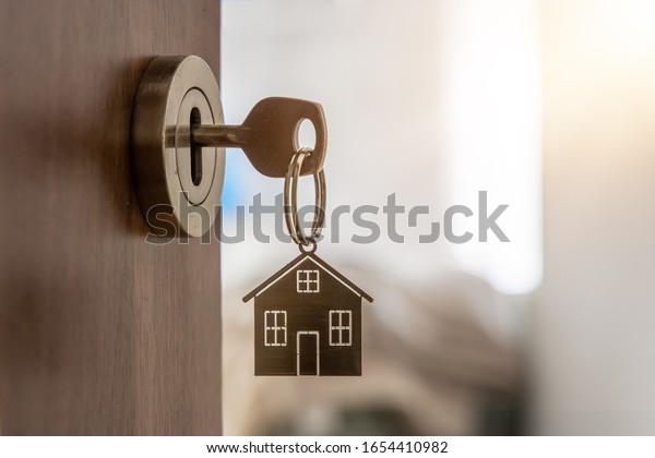 Open door to a new home with key and home shaped\
keychain. Mortgage, investment, real estate, property and new home\
concept