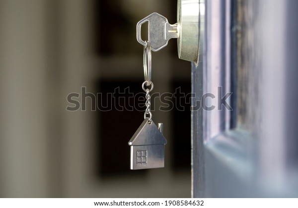 Open door to a new home with key and home shaped\
keychain. Mortgage, investment, real estate, property and new home\
concept business