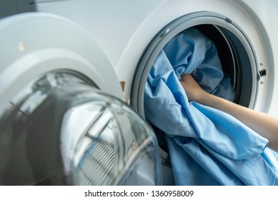 Open Door In Washing Machine With Blue Bed Sheets Inside Close Up.