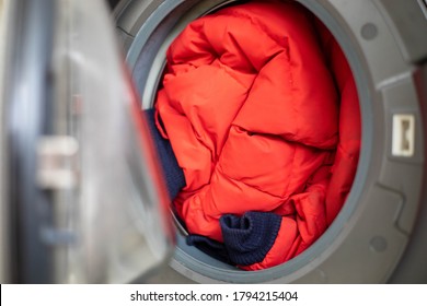 Open door in washing machine with dirty down jacket inside, close up, preparation for cleaning, copy space