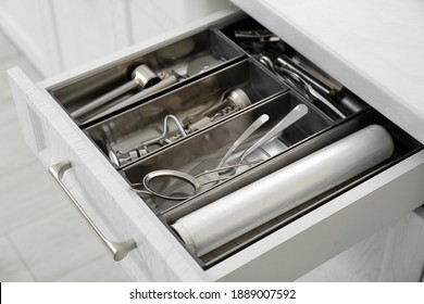 Cajón abierto con diferentes utensilios en la cocina, armario
