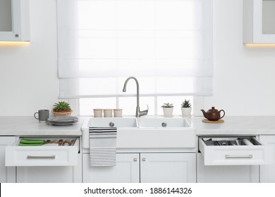 Open drawers with different utensils, towels and napkins in kitchen