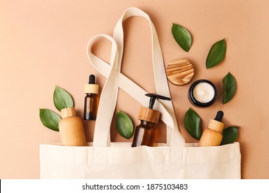 Open eco friendly cotton reusable bag with the different containers from the natural wood and brown glass.Fresh natural leafs around.Concept of organic,zero waste cosmetics.Woman bag with ac?essories. - Shutterstock ID 1875103483