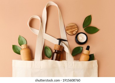 Open eco friendly cotton reusable bag with the different containers from the wood and glass.Pastel colors.Fresh natural leafs around.Concept of organic,zero waste cosmetics.Woman bag with accessories. - Shutterstock ID 1915608760