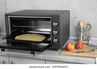 Horno eléctrico abierto con masa en la encimera de la cocina