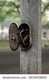 Open electrical access panel on a metal street light pole exposing twisted wires.