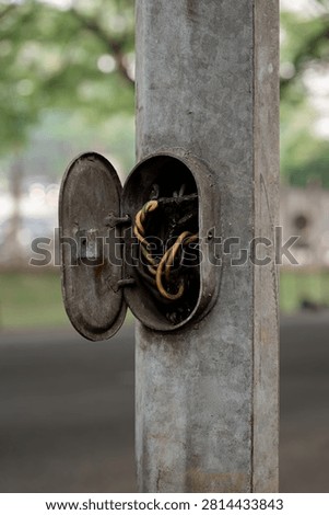 Open electrical access panel on a metal street light pole exposing twisted wires.