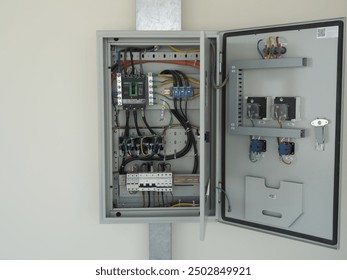 An open electrical panel with a 3-phase automatic transfer switch, circuit breakers, and various electrical components
