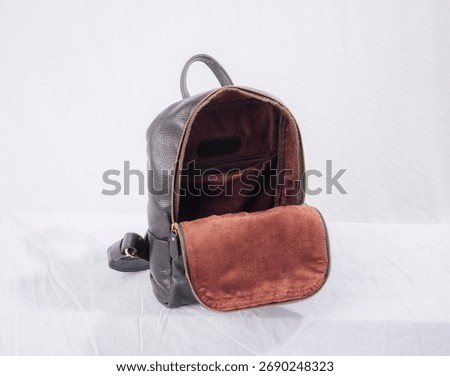 Open and empty black leather backpack isolated on white background