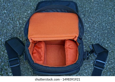 open empty black red camera bag lies on gray asphalt