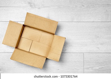 Offener leerer Karton auf Holzfußboden
