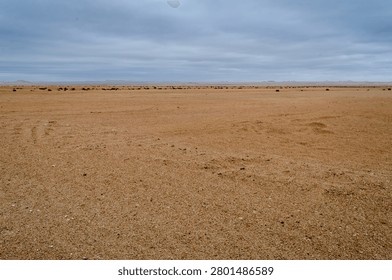 Open, empty, desolate sand landscape against a cloudy sky, unbounded, breathing space
