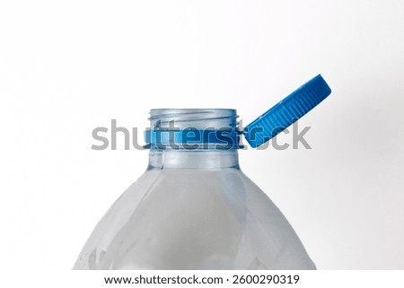 Open empty plastic bottle with blue cap, showing its threaded neck and tamper evident ring, isolated on white background