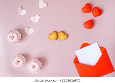 an open empty red envelope with a heart lies in the center on a pink background, heart-shaped cookies, white paper valentines, confetti, red candles, pink marshmallows lie nearby - Powered by Shutterstock