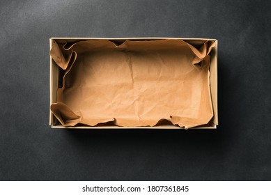 Open Empty Shoe Box, Isolated On A Black Background. Crumpled Brown Paper. Packaging For Men's And Women's Shoes Or Delivery Of Goods From The Store. A Top View Of A Flat Layout