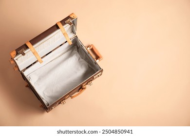 Open empty suitcase on beige background, top view. Space for text