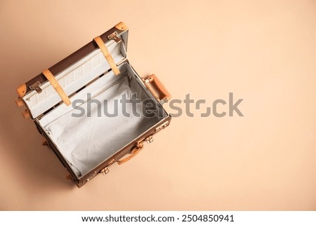 Open empty suitcase on beige background, top view. Space for text