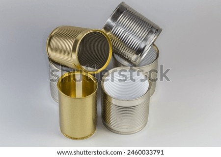 Open empty tin cans from under a canned food, different sizes with various white and yellow covering on a gray background 