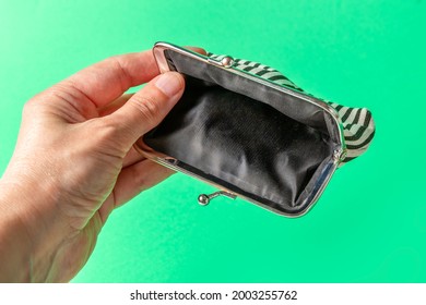 Open Empty Wallet In Hand On A Green Background. Poverty Concept. Below The Poverty Line. High Quality Photo