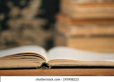 Open End Of The Old Book On A Wooden Boards Background On A Pile Of Books