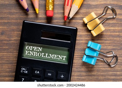 Open Enrollment. Calculator And Office Supplies On A Wooden Table.