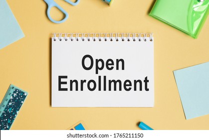 Open Enrollment. Notebooks, pen and colored pencils on a wooden table.