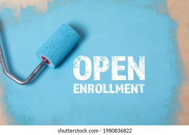 Open Enrollment. Paint roller with blue paint on a wooden surface.