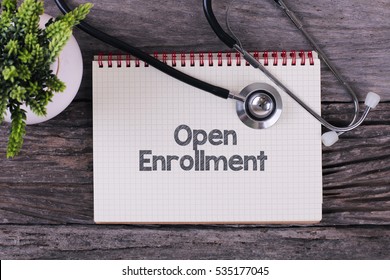 Open Enrollment word on notebook,stethoscope and green plan
